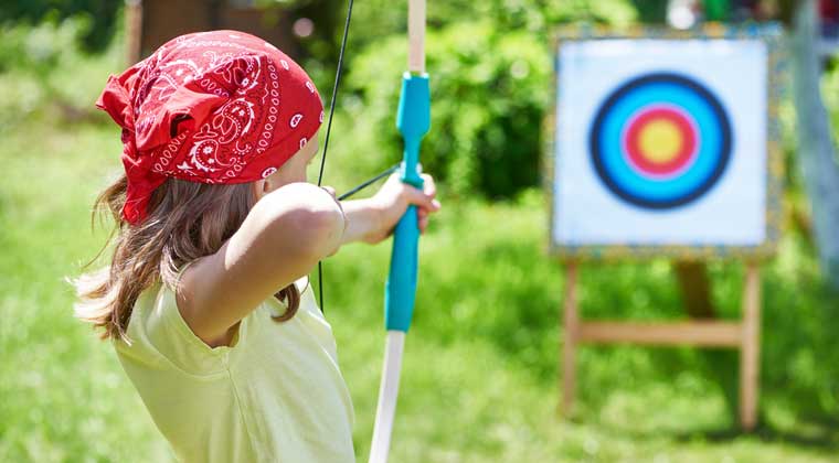 girl shooting bow and arrow at target