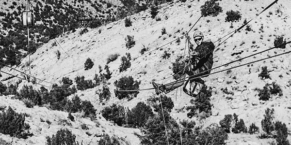 man servicing a zipSTOP Zip Line Brake on a zip line in black and white