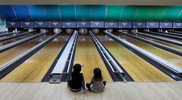 kids sitting in front of bowling lane