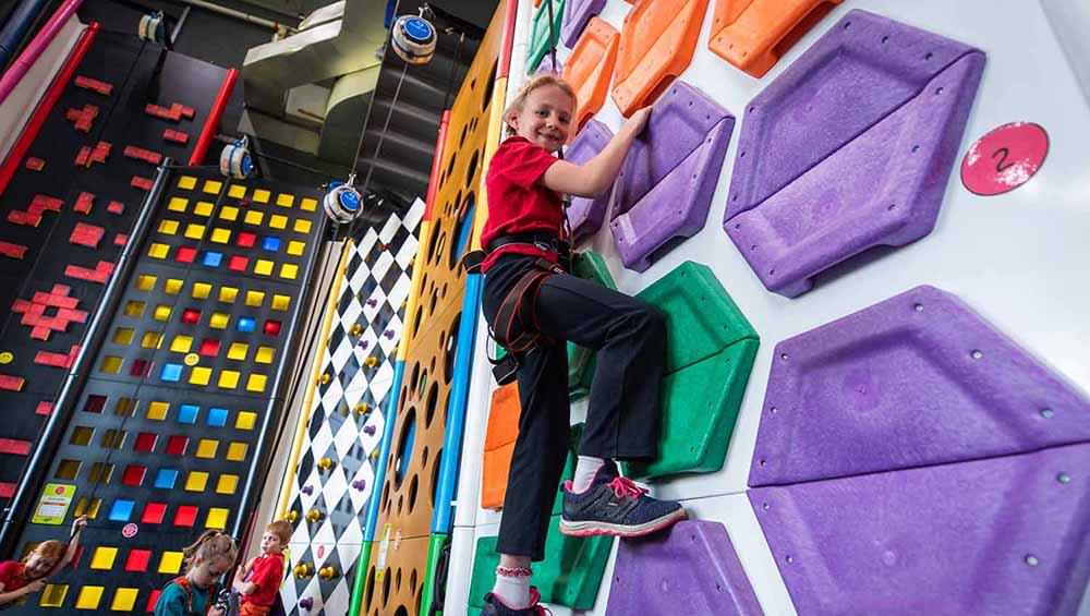 Male child climbs TRUBLUE auto belay at Family Entertainment Center